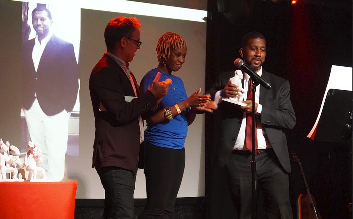 An award presentation on stage with the honoree's photo on screen