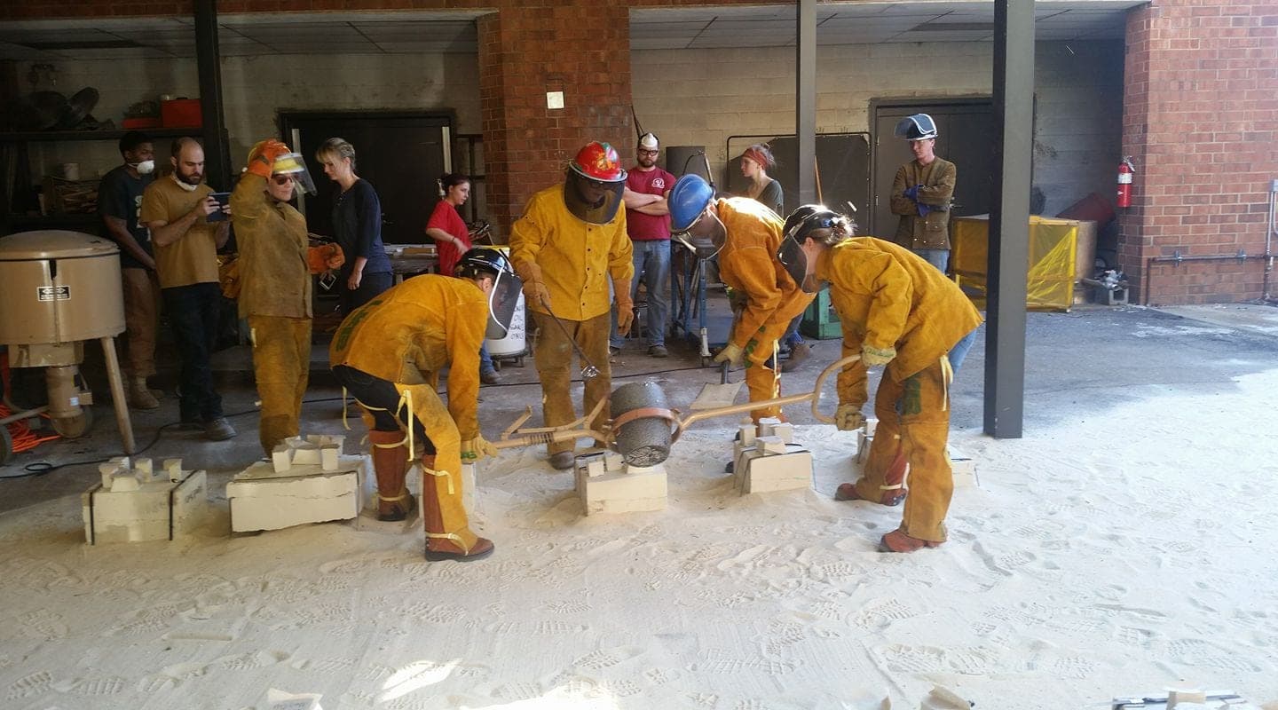 UAB art students in protective gear pouring molten metal to cast trash from the Lake Purdy cleanup into art