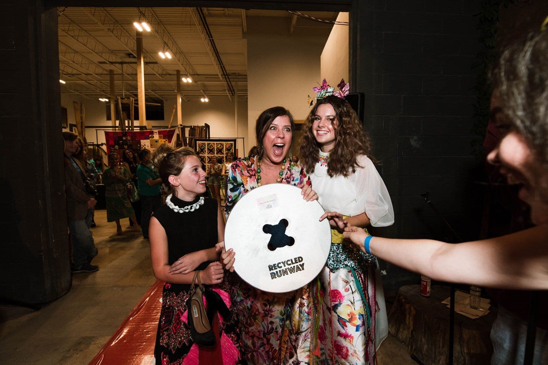 Guests laughing and holding a Recycled Runway sign