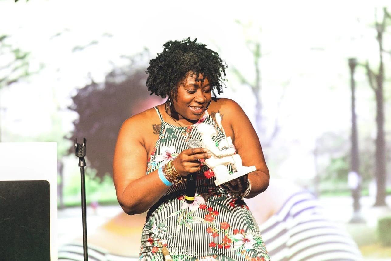 An honoree smiling as she holds her award on stage